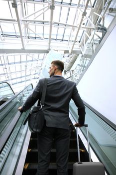 Businessman at the airport going down the escalator.