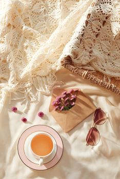 Flowers in envelope with glasses and cup of tea on fabric background 