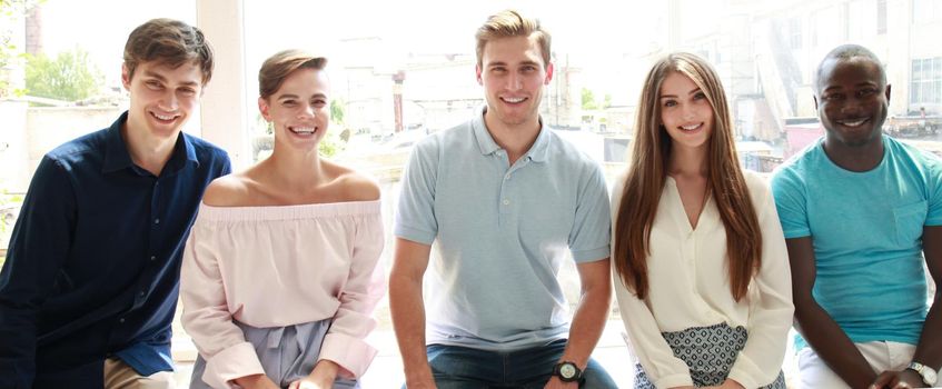 Young people looking at camera with smile while sitting in the office.