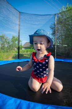 One and a half year old child in Panama and in a dress is afraid to jump on the trampoline