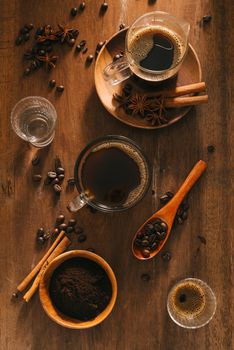 Cup of coffee with water, coffee beans, cinamon on wooden background