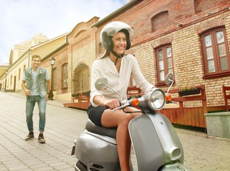 happy young couple riding scooter in town. Handsome guy and young woman travel. Adventure and vacations concept.