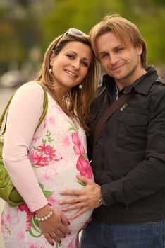 Happy and young pregnant couple have fun and relax outdoor