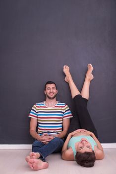 happy pregnant couple relaxing in front of black chalkboard on the floor at home