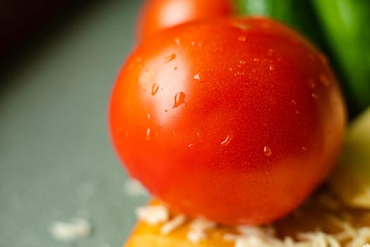 Picture with focus on washed red tomato lies on the table with drops of water on it