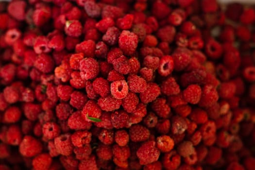 Top view of heap of red ripe raspberries after harvesting. Pile of fresh and delicious raspberries.