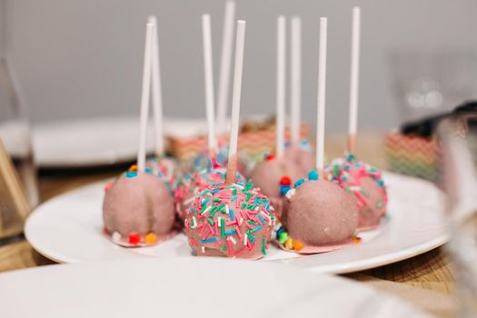 picture of many small pink pastries with sprinkles on a large white plate on a table