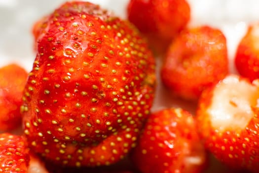 Macro stock photo of large organic sweet strawberries in sunlight. Strawberry texture in close-up. Seeds and dirt.