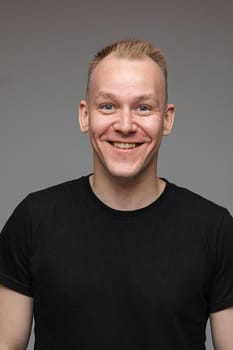 adult caucasian man in black t-shirt and short hair looks to the camera and smiles
