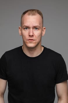 adult caucasian man in black t-shirt and short hair looks to the camera and smiles