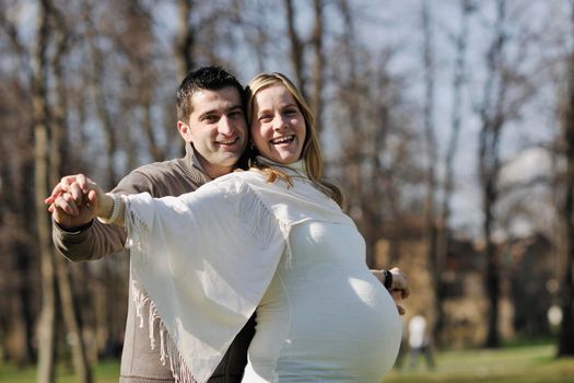 happy young married family couple outdoor in nature have fun and waiting baby and representing young family growth and pregnancy concept