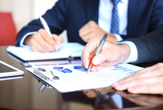 Two young businessmen analyzing financial document at meeting.