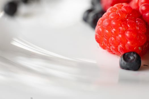 Close up of fresh organic summer berries mix in white plate. Healthy food concept. Copy space