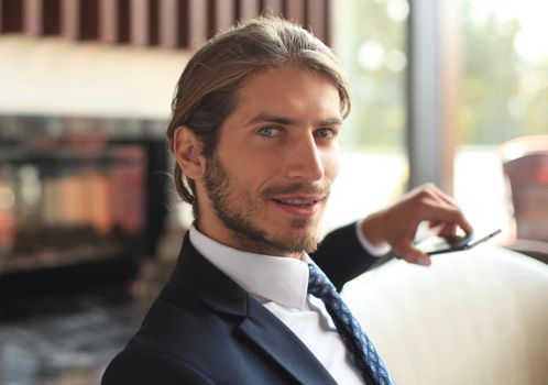 Portrait of happy young businessman sitting on sofa in hotel lobby
