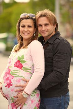 Happy and young pregnant couple have fun and relax outdoor