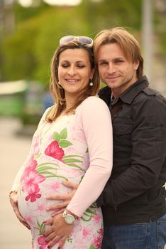 Happy and young pregnant couple have fun and relax outdoor