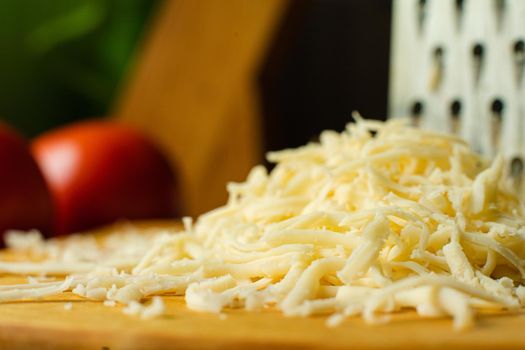 Picture of metal kitchen grater with oval holes on it on the kitchen table with cheese