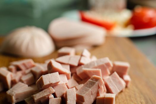 Picture of a small pile of cube sliced sausage for cooking on a wooden table in the kitchen