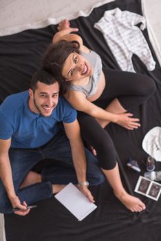 top view of a happy pregnant couple checking a list of things for their unborn baby at home on the floor