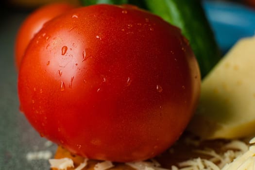 Picture with focus on washed red tomato lies on the table with drops of water on it