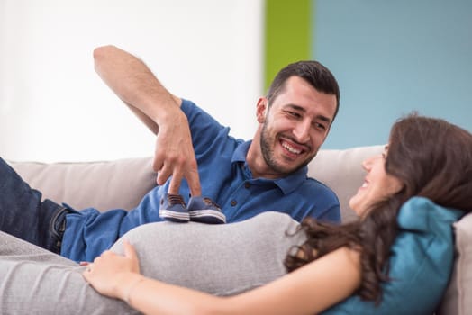 happy pregnant couple relaxing on sofa couch at home