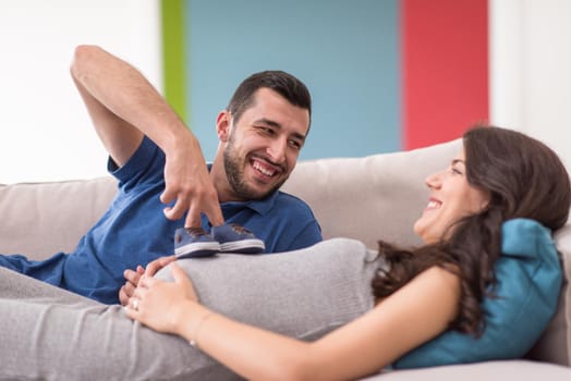 happy pregnant couple relaxing on sofa couch at home