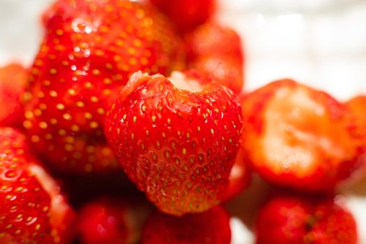 Macro stock photo of large organic sweet strawberries in sunlight. Strawberry texture in close-up. Seeds and dirt.