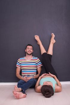 happy pregnant couple relaxing in front of black chalkboard on the floor at home