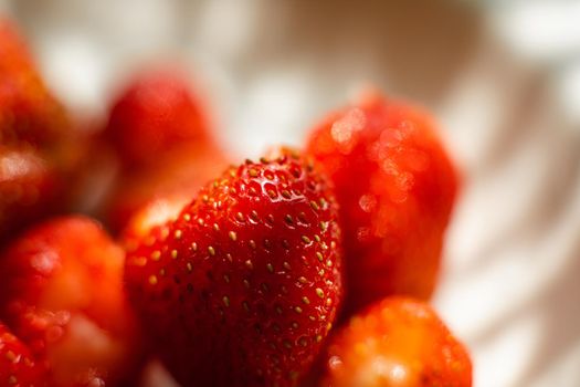 Macro stock photo of large organic sweet strawberries in sunlight. Strawberry texture in close-up. Seeds and dirt.