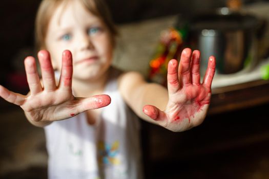 Happy child girl standing and holding her hands dirty with paint at camera. Childhood and creativity concept