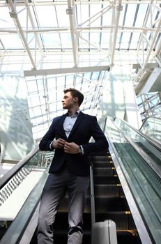 Businessman at the airport going down the escalator.