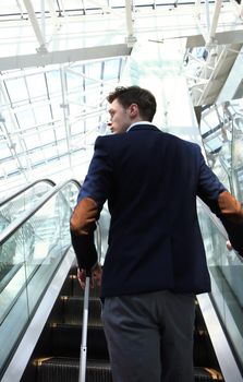 Businessman at the airport going down the escalator.