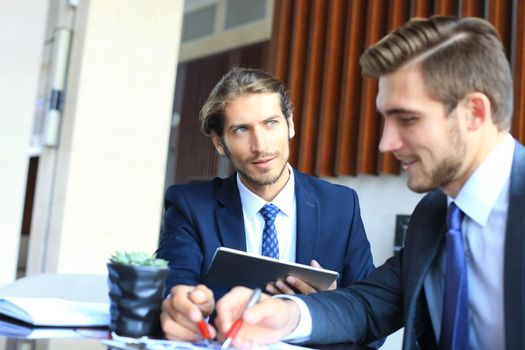 Two young businessmen analyzing financial document at meeting.