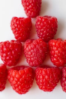 A picture of a few fresh pink raspberries lies on a white background. Background and picture for postcard.