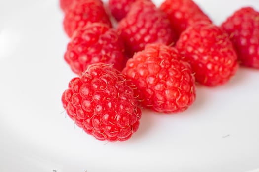 A picture of a few fresh pink raspberries lies on a white background. Background and picture for postcard.