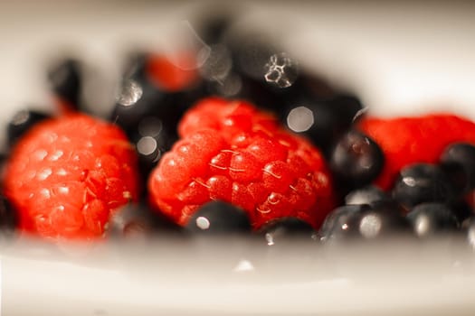 picture of juicy fresh ripe red strawberry berries in a white ceramic plate on the table under bright sunlight