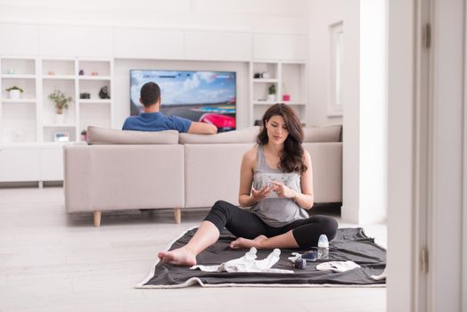 a happy pregnant couple checking a list of things for their unborn baby at home on the floor