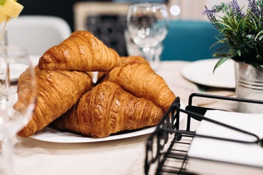 Close up photo of a pile of freshly-baked croissants on a plate sitting on the table