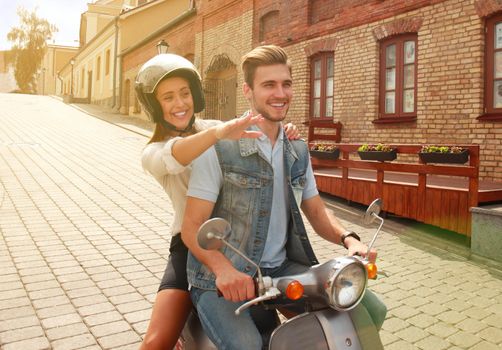 happy young couple riding scooter in town. Handsome guy and young woman travel. Adventure and vacations concept.