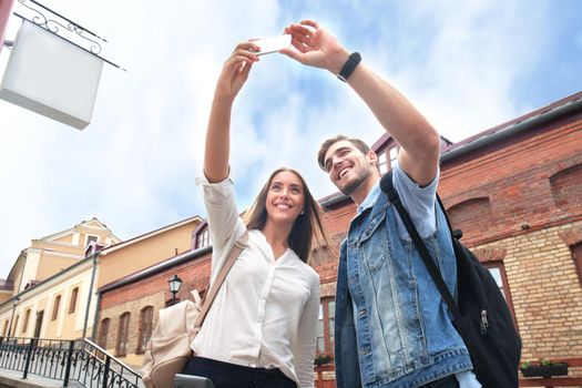 Happy couple of tourists taking selfie in old city.