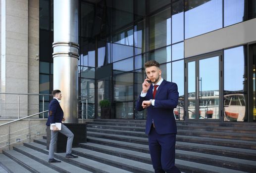 Young urban businessman professional on smartphone walking in street using mobile phone.