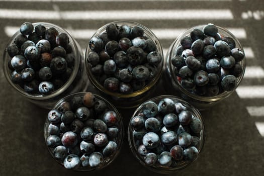 Many large beautiful juicy fresh blueberries lie in glass jars.