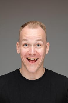 adult caucasian man in black t-shirt and short hair looks to the camera with a big smile