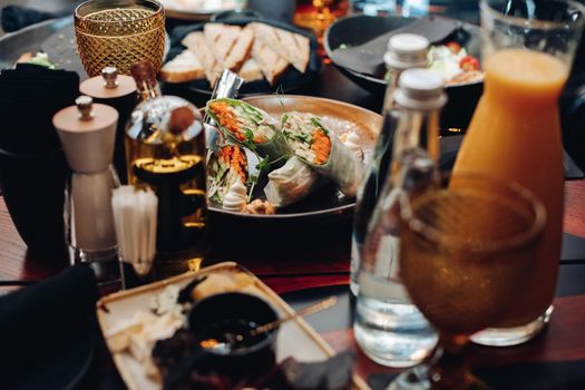 Stock photo of vegetable rolls with cucumber, carrot and greens in rice paper served on plate on table in restaurant.