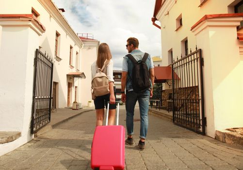 Two travelers on vacation walking around the city with luggage.