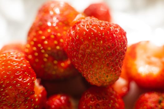 Macro stock photo of large organic sweet strawberries in sunlight. Strawberry texture in close-up. Seeds and dirt.