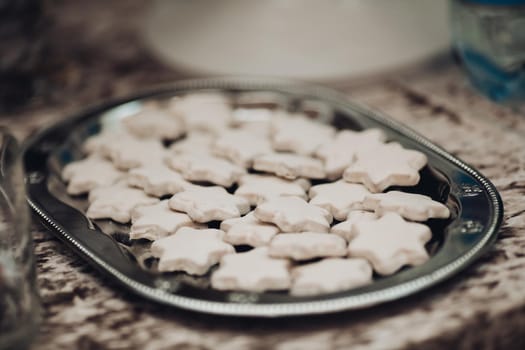 picture of a big silver plate with a lot of white star cookies on the table