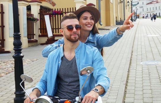 happy young couple riding scooter in town. Handsome guy and young woman travel. Adventure and vacations concept.