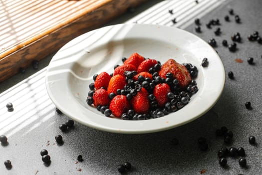 picture of juicy fresh ripe red strawberries in a white ceramic plate with light background