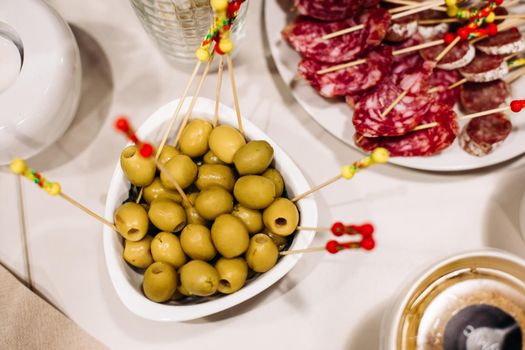 Catering, close up top view of festive appetizing olives, sausage slices, healthy snacks on banquet table, party dining. High quality photo
